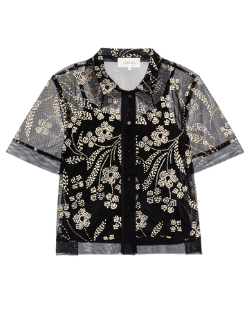 The Cotillion Top from THE GREAT. H25 COLLECTION features brocade floral patterns in white and gold dots on a black sheer, short-sleeved design with a collar.
