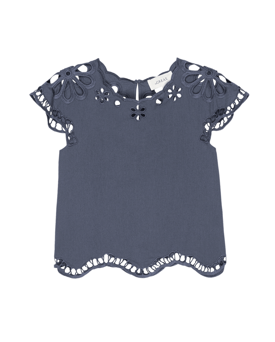 The Super Bloom Eyelet Top by THE GREAT. SU25 in vintage blue features floral cutout details, scalloped hems, and a back button closure—perfect for a standout super bloom look.
