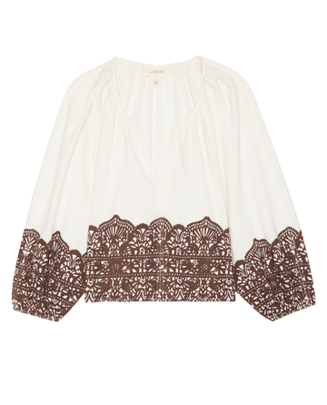 The Chariot Top by THE GREAT. F25 D1 is a cream cotton top with Western lace print at the hem and cuffs, featuring a v-neck and gathered sleeves.