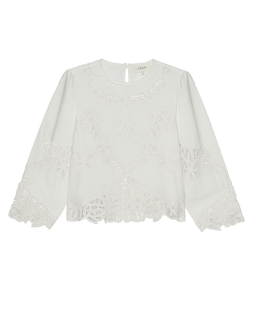 The Picnic Top in Cream by THE GREAT. PS26 is a white long-sleeve blouse made of structured cotton, featuring Battenburg lace embroidery on the sleeves, hem, and front, with a round neckline and keyhole button closure at the back.