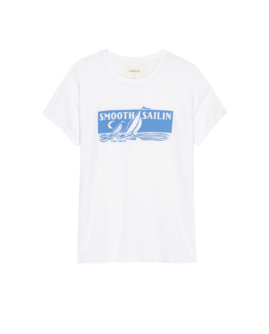The Boxy Crew. Graphic in True White from THE GREAT. SU25 features a playful "Smooth Sailin" blue sailboat graphic, perfect for adding fun to your casual style.