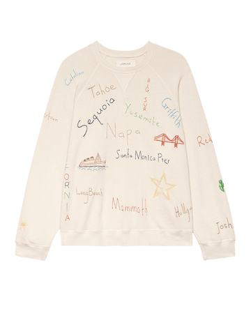 The Slouch Sweatshirt by THE GREAT. F25 D2 is a washed white, vintage-inspired top featuring Golden State embroidery, hand-drawn style illustrations, and multicolored names of California locations and icons.