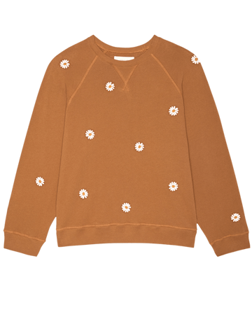 THE GREAT.'s Slouch Sweatshirt in Suntan features floating white daisy embroidery on the front and sleeves, displayed on a plain background.