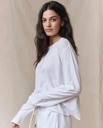 A woman wearing THE GREAT. CORE KNITS The Long Sleeve Crop Tee in True White.