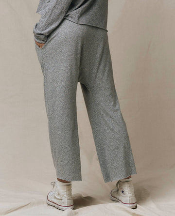 Someone wearing THE GREAT. CORE KNITS The Jersey Crop Pant in Heather Grey and white high-top sneakers, photographed from the back against a neutral background.
