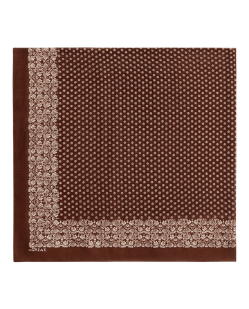 THE GREAT. F26 BIG BANDANA – The Big Bandana in Chocolate features a white floral and dot pattern on a brown square, with decorative borders along two edges reminiscent of a vintage handkerchief.