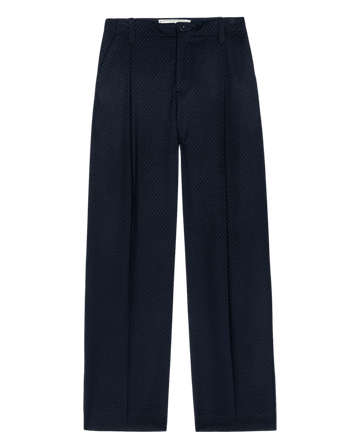 The Menswear Trouser Pant. -- Navy Jacquard by THE GREAT. F26 COLLECTORS is a pair of straight-leg trousers in dark navy with a subtle dotted jacquard pattern, featuring belt loops, front pleats, and a button-zip closure, shown on a plain white background.