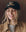 A woman wearing THE GREAT. F25 D1 ACCESSORIES The Baseball Hat. Graphic -- Black, featuring "THE GREAT" in chainstitch embroidery, smiles while looking slightly down, paired with a tan jacket and gray top.