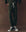 Person wears The Stadium Sweatpant. Novelty -- Forest Camo by THE GREAT. F25 D1, handcrafted in Los Angeles, with black high-top Converse sneakers, standing against a brown background.