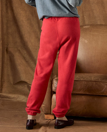 Back view of a person wearing The Fleece Stadium Sweatpant in Campfire, featuring red fleece sweatpants with elastic cuffs styled with dark loafers.