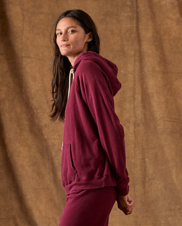 THE GREAT. H26 FLEECE BACK KNITS The Fleece Pullover Hoodie in plum, featuring a hood and white drawstring.