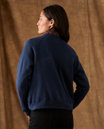 A person viewed from the back, wearing THE FLEECE ROOKIE SWEATSHIRT -- TRUE NAVY with raglan sleeves and cozy fleece.