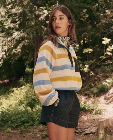 Someone outdoors in The Excursion Pullover by THE GREAT. SP25 TGO and shorts, standing on a wooded path.