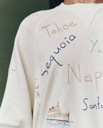 Close-up of THE GREAT. F25 D2’s The Slouch Sweatshirt in washed white, featuring multicolored "Golden State" embroidery—like "Tahoe," "Sequoia," and "Napa"—plus a small boat illustration for a vintage-inspired look.