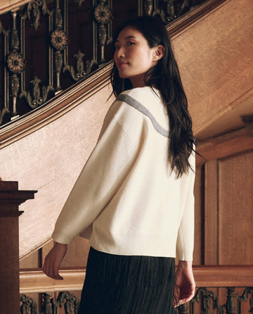 A person from the back wearing The Bow Sweater in cream, featuring a dark, textured horizontal stripe across the shoulders.