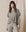 A person in THE GREAT. CORE KNITS' Heather Grey Crop Tee and matching drawstring pants stands against a beige fabric backdrop.
