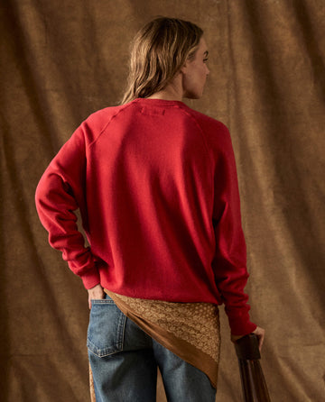Back view of a person wearing THE GREAT. H26 FLEECE BACK KNITS, The Fleece College Sweatshirt in Campfire, and blue jeans.