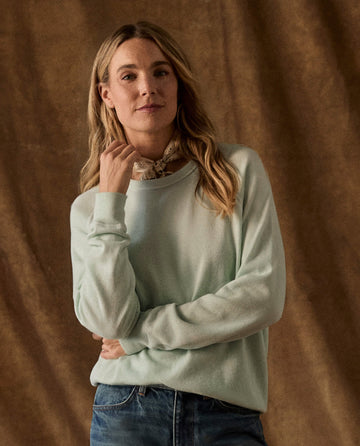 A woman wearing The Fleece College Sweatshirt in Fresh Mint with blue jeans and a patterned neckerchief.