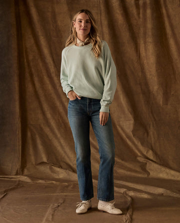 Woman wearing The Fleece College Sweatshirt in Fresh Mint, blue jeans, and light-colored shoes.