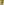 A person in a light green blouse and THE GREAT. SP25 SWIM The Delta Short in Citron stands by a swimming pool, with greenery in the background.