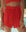 Standing outdoors near a swimming pool, this person wears stylish red apparel featuring THE GREAT. SP25 SWIM's The Delta Short in Hot Red.