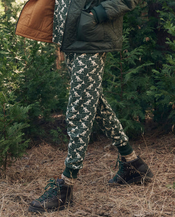 A person wearing The Union Long John in Spruce, featuring a skier print, tucked into dark hiking boots.