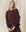 A person with long, blonde hair wears "The College Sweatshirt" in Toasted Walnut by THE GREAT. FALL 24 KNITS, along with matching brown pants, standing in front of a beige background.