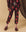 Clad in The Hand Stamped Stadium Sweatpant by THE GREAT. HOL 24 BIRKENSTOCK, featuring a mocha hue peppered with hot red daisy patterns, paired with matching top and complemented by pink speckled socks and black shoes, the individual stands against the backdrop, their vibrant attire effortlessly catching every eye.