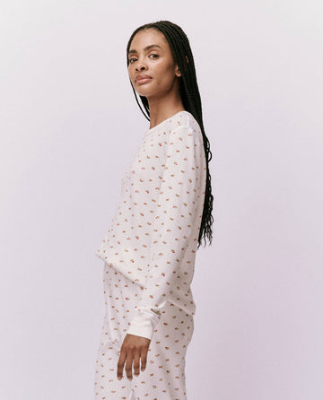 A person wearing The Waffle Surplus Crew in White Mini Heirloom Rose by THE GREAT. HOL 24 ROSEBUD CAPSULE stands sideways against a plain backdrop.