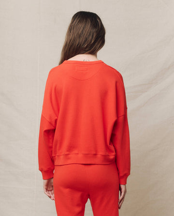 A person with long hair wears The Teammate Sweatshirt by THE GREAT. SP25 KNITS in Tart, paired with matching pants, facing away against a plain background.