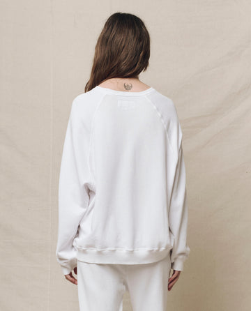 A person in a vintage True White Slouch Sweatshirt and matching pants from THE GREAT. HOL 24 KNITS stands with their back to the camera, long hair cascading down to reveal a small neck tattoo.
