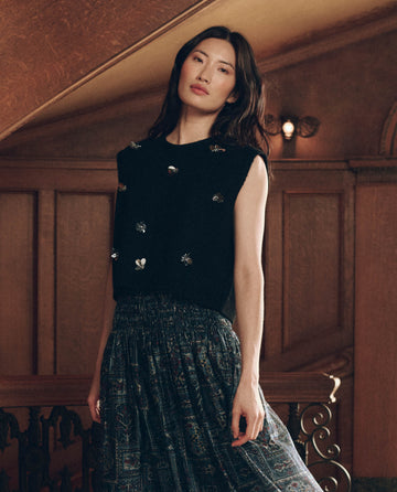 A model wearing The Embellished Sweater Vest. -- Black with silver details and a dark patterned midi skirt.