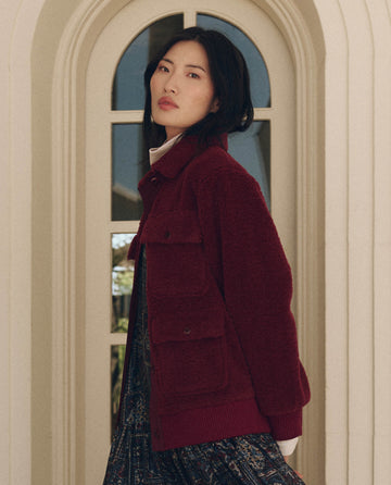 A person wearing a maroon The Patch Pocket Plush Jacket featuring two large patch pockets on the chest.