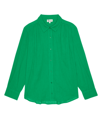 The Cove Shirt by THE GREAT. SP26 SWIM in Bright Sprig is a long-sleeve green button-up with a pointed collar, pleated shoulder details, and a curved hem, shown on a white background.