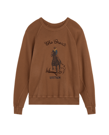The College Sweatshirt w/ Stetson Graphic in Tobacco by THE GREAT. F26 STETSON features a vintage-style illustration of a person riding a horse and is adorned with “THE GREAT.” and “STETSON” on the front—a stylish collaboration piece.