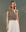 A person with long hair wears The Midland Top in Heirloom Paisley by THE GREAT. SP25 D2, paired with a white skirt, standing against a textured background.