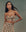 A person in a stylish ensemble of "The Bustier Top – Heirloom Paisley" by THE GREAT. SP25 D2 and a matching skirt stands against a muted background, epitomizing refined women's clothing.