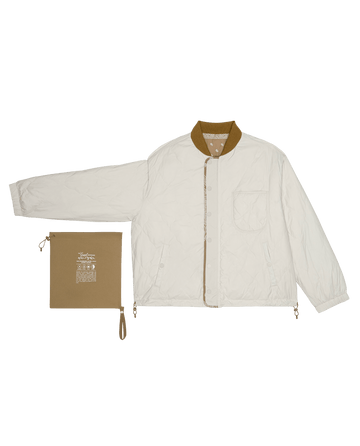The Reversible Ultra Light Puffer by THE GREAT. SP26 TGO in Khaki Bandana W/ Cream features a white quilted design, tan collar and placket, front pockets, plus a matching tan zip pouch. Lightweight and perfect for layering year-round.