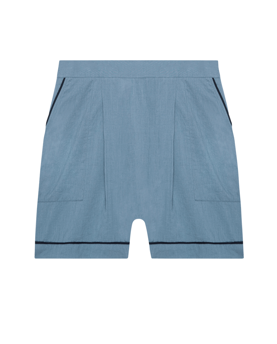 The Square Pajama Short in Blue Dusk by THE GREAT. SP25 SLEEP features front pleats, side pockets, and black trim on the edges and hem, shown against a plain background.