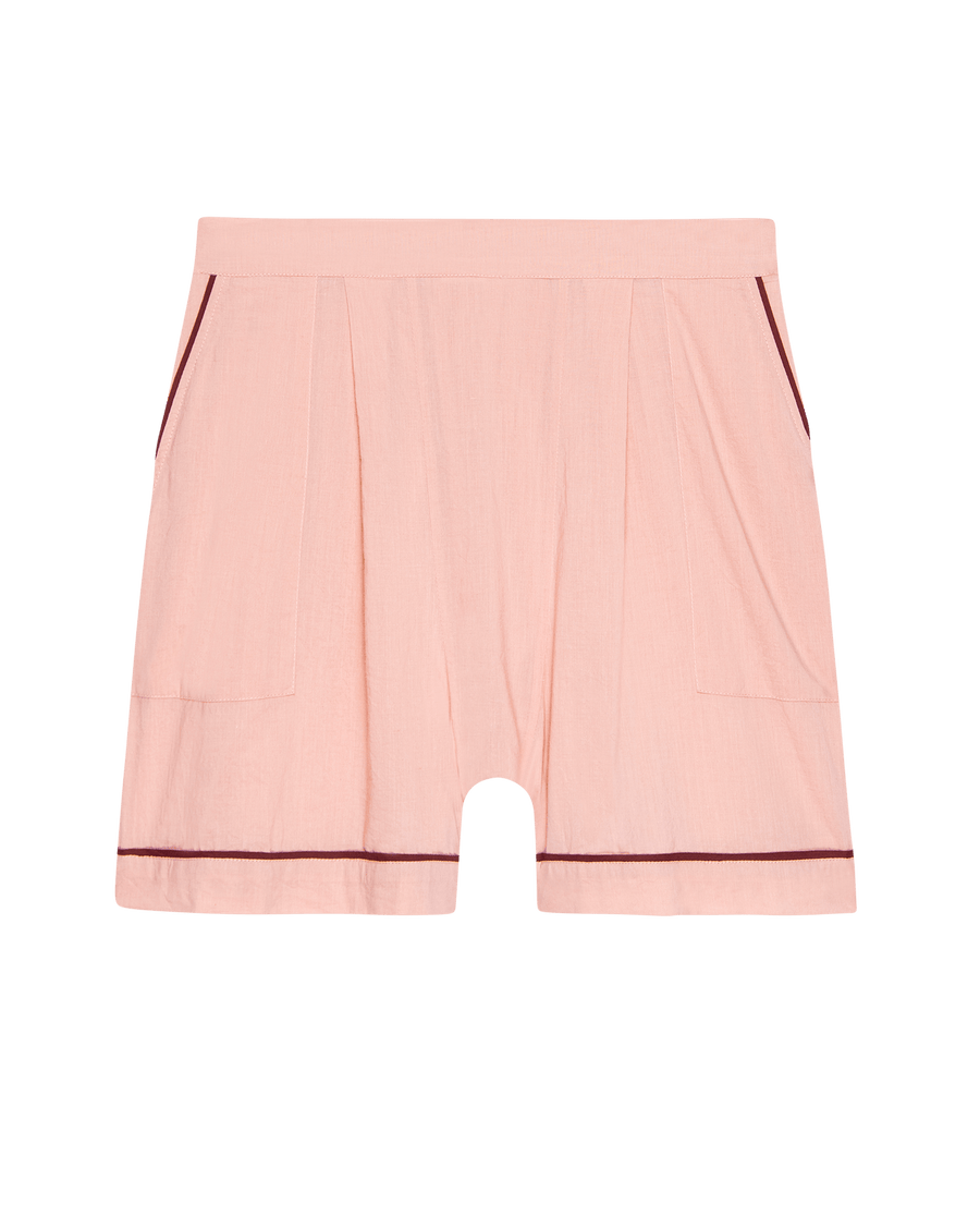 The Square Pajama Short in Rose Bloom by THE GREAT. SP25 SLEEP features a light pink hue, high-waisted fit, front pleats, side pockets, and dark trim at the pockets and hem.