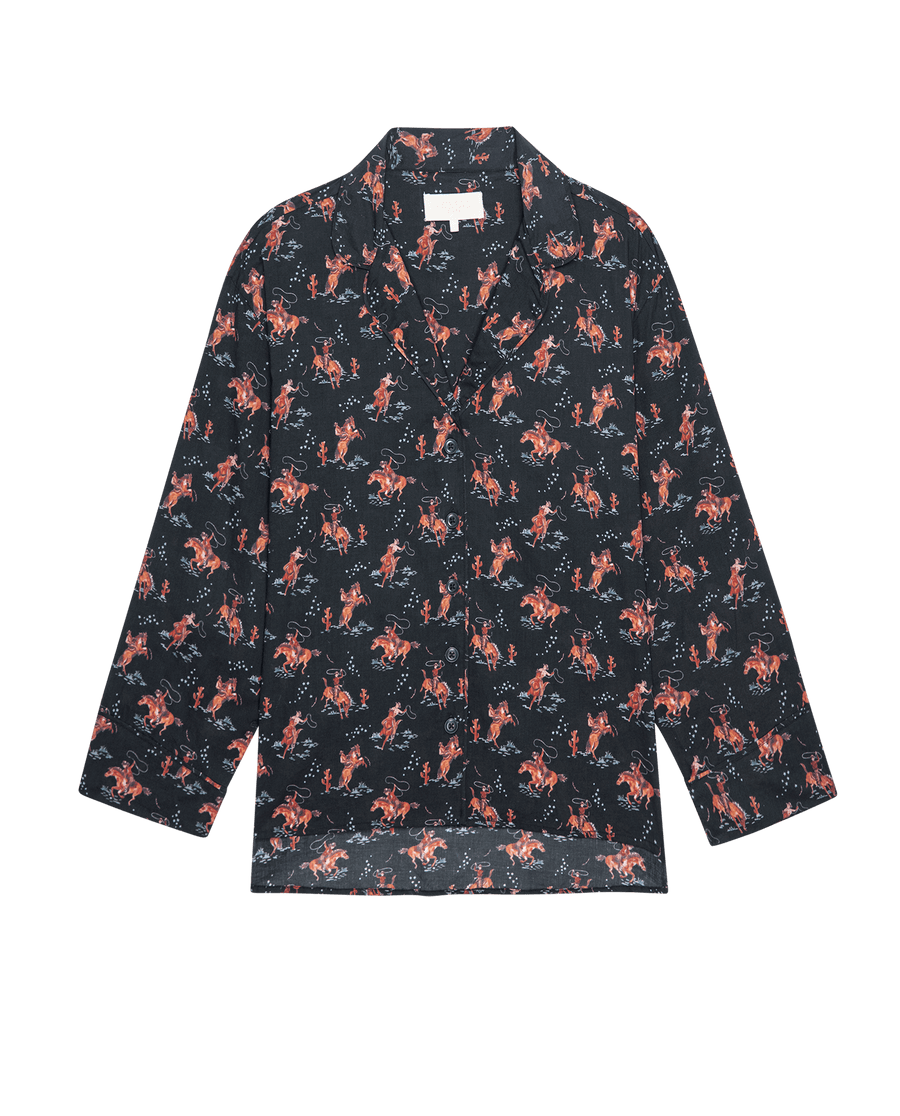 The Pajama Shirt. -- Navy Cowboy by THE GREAT. SP25 SLEEP is a stylish long-sleeve, button-up sleep shirt featuring a navy base with an all-over cowboy print—perfect for chic sleepwear.
